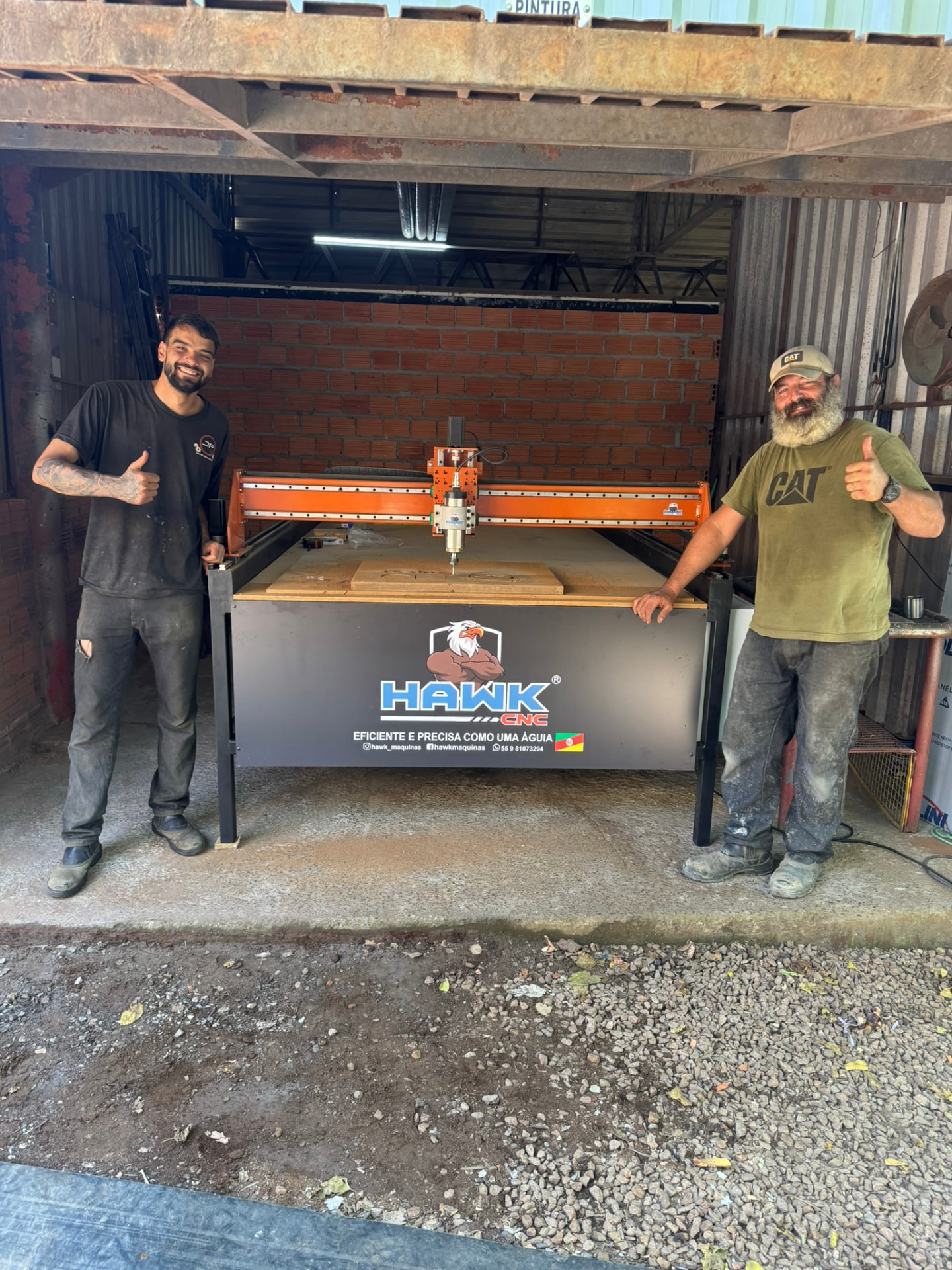 Dois clientes ao lado da Router CNC Hawk recém-entregue